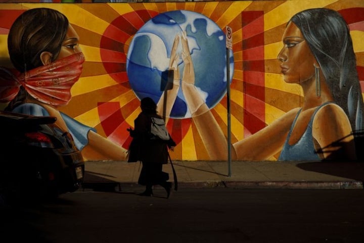 A pedestrian walks past the mural “¡Resiste!” by Nanibah Chacon outside Self-Help Graphics & Art, Inc.