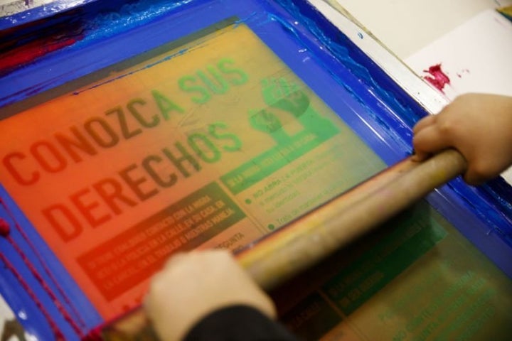 A young artist with Self Help Graphics & Art prints posters for renters reading “Conozca Sus Derechos” (Know
