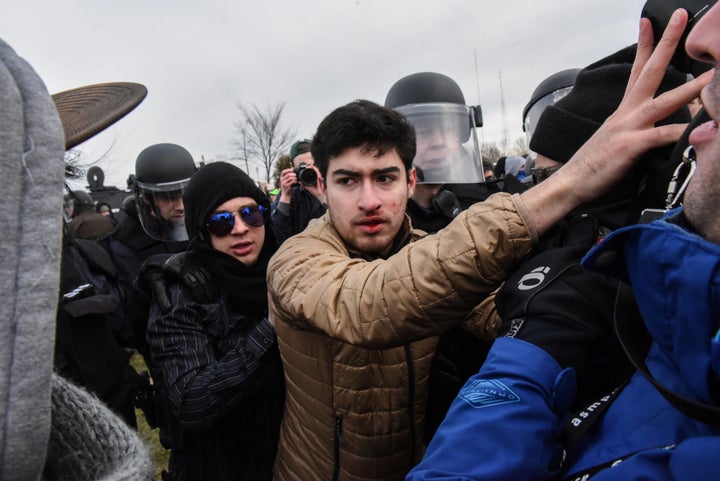 Police officers escort a man through protesters to the Richard Spencer speech on March 5, 2018.