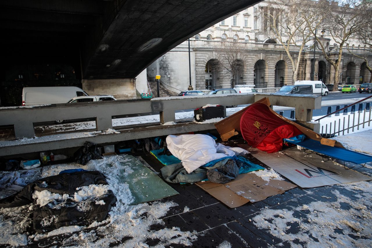 Bedding and shelters belonging to homeless people lie under a bridge covered in snow on the Embankment in London during the cold snap