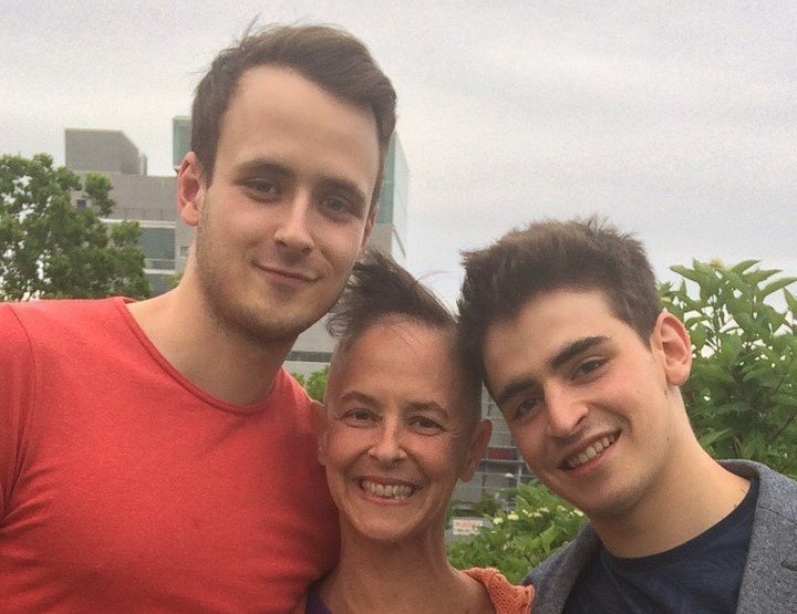 Susan, with her hair mostly out from chemo, and her sons Oliver (left) and Nathan (right) at Nathan's graduation from the National Circus School (background). 