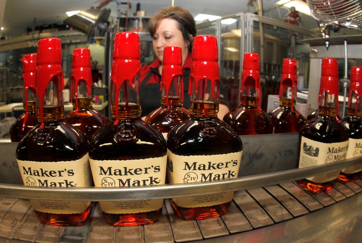 New bottles of Maker's Mark bourbon on the conveyor belt pass by a worker after being hand dipped with their signature red wax, on their way to packaging at the Maker's Mark Distillery plant in Loretto, Kentucky January 23, 2014.