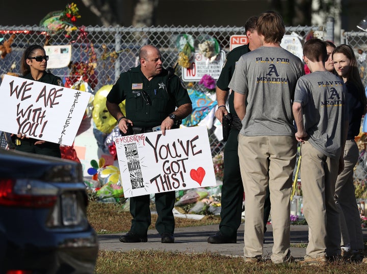 Police officers from Broward County welcome students as they arrive at Marjory Stoneman Douglas High School for their first day of classes after a deadly mass shooting at the school. 