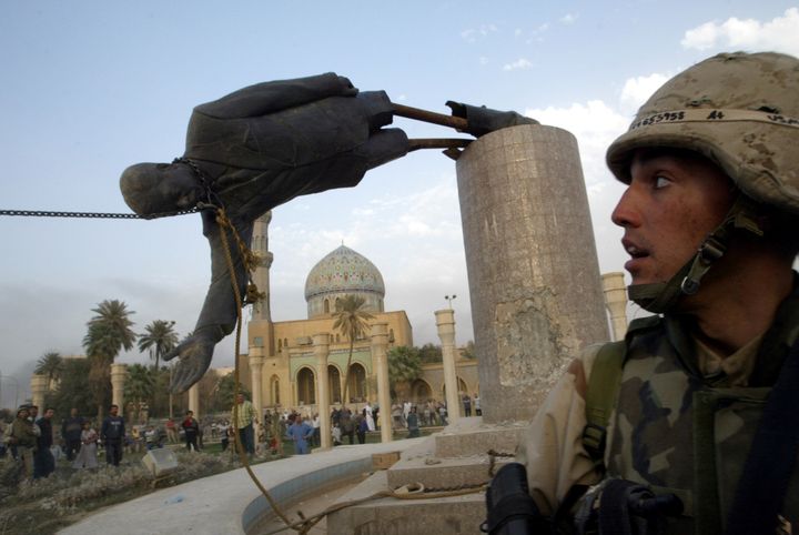 A U.S. soldier watches as a statue of Iraq's President Saddam Hussein falls in central Baghdad, Iraq, April 9, 2003.
