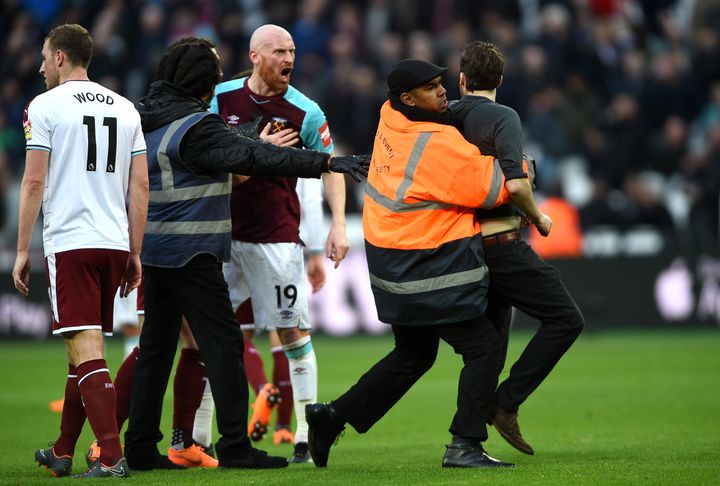 A Pitch invader is confronted by security during the Premier League match at the London Stadium.