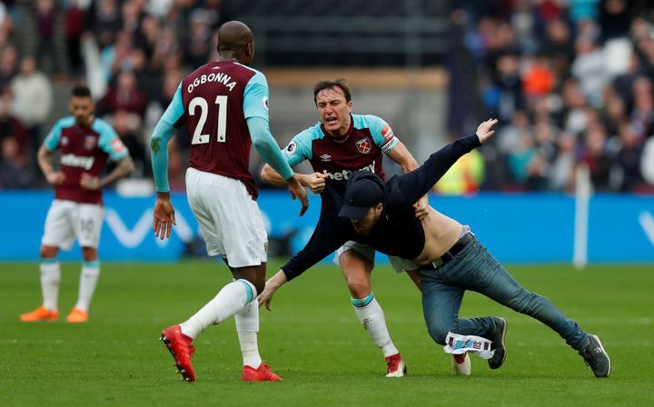 West Ham United's Mark Noble clashes with a fan who has invaded the pitch.
