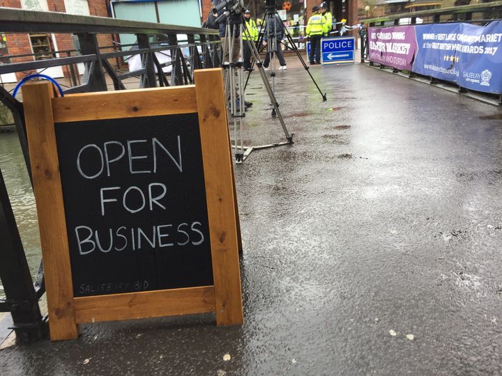 A sign reassures passersby the shops near the cordon are still open