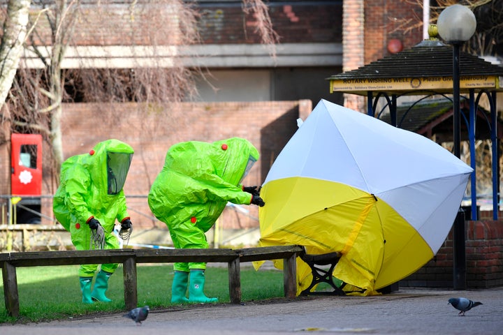 Members of emergency services in green biohazard encapsulated suits fix a tent over the bench where Sergei Skripal and his daughter were found on March 4 in critical condition in Salisbury, England.