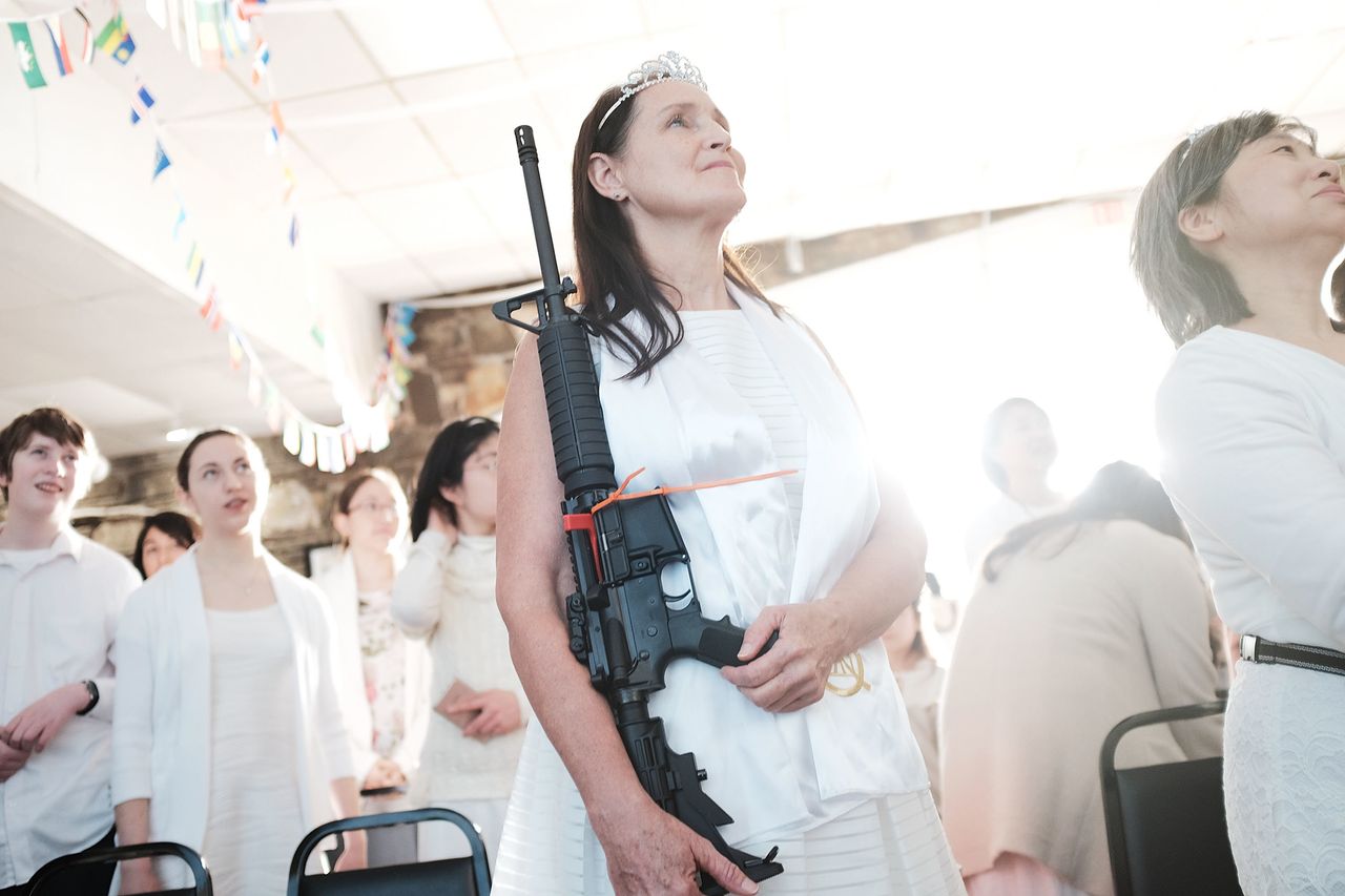 A woman holds an AR-15 rifle during a ceremony at the World Peace and Unification Sanctuary on Feb. 28 in Newfoundland, Pennsylvania. The controversial church, led by the son of the late Rev. Sun Myung Moon, believes the AR-15 symbolizes the "rod of iron" in the biblical Book of Revelation. An attachment to the gun culture has similar threads to beliefs in religion and pseudoscience.