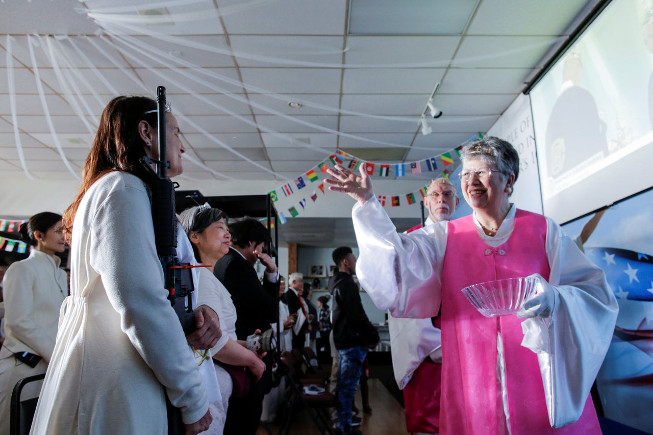 A church official throws holy water on an AR-15-style rifle while people attend a blessing ceremony with their weapons at the Sanctuary Church in Newfoundland, Pennsylvania. 