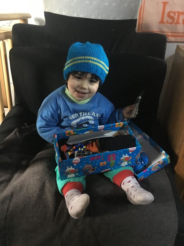 One of the recipients beams while opening a Christmas shoebox filled with essentials. 