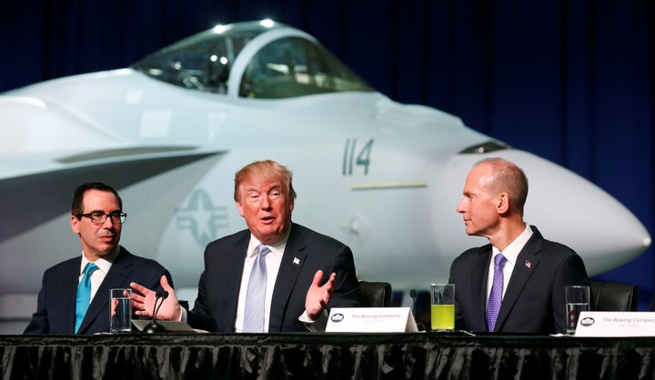 President Donald Trump sits between Treasury Secretary Steve Mnuchin (L) and Boeing Chairman and CEO Dennis Muilenburg (R) du