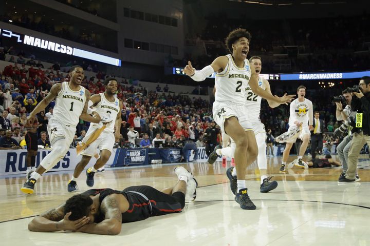 Jordan Poole and teammates celebrate Poole's 3-point buzzer beater for a 64-63 win as Devin Davis of the Houston Cougars is seen on the ground.