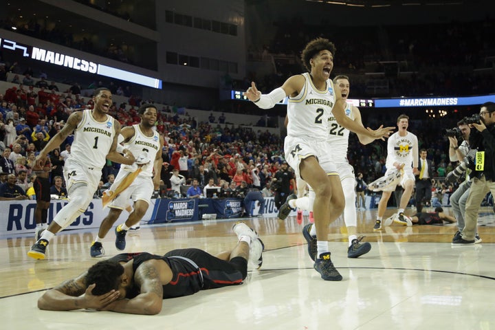 Jordan Poole and teammates celebrate Poole's 3-point buzzer beater for a 64-63 win as Devin Davis of the Houston Cougars is seen on the ground.