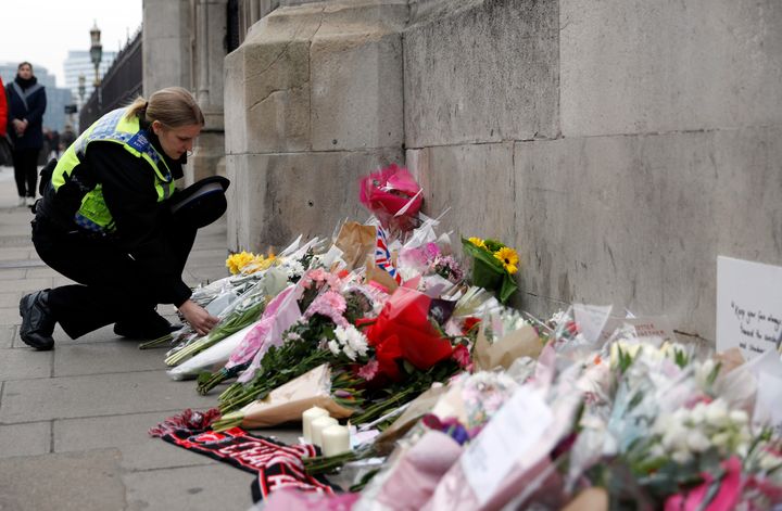 A police officer lays a floral tribute near Westminster Bridge following the attack