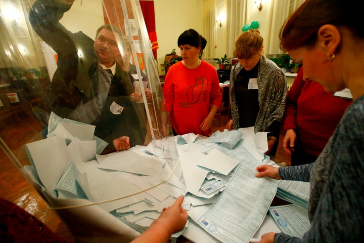 Members of a local election commission empty a ballot box before starting to count votes during the presidential election at a polling station in a settlement in Smolensk Region, Russia March 18, 2018.