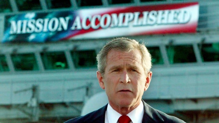 George W. Bush stands in front of the infamous "Mission Accomplished" banner on the USS Abraham Lincoln to declare the end of combat operations in Iraq.