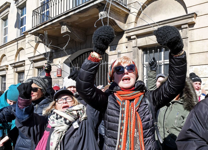 People hold up wire hangers as they demonstrate in front of the seat of the Warsaw archdiocese on March 18.