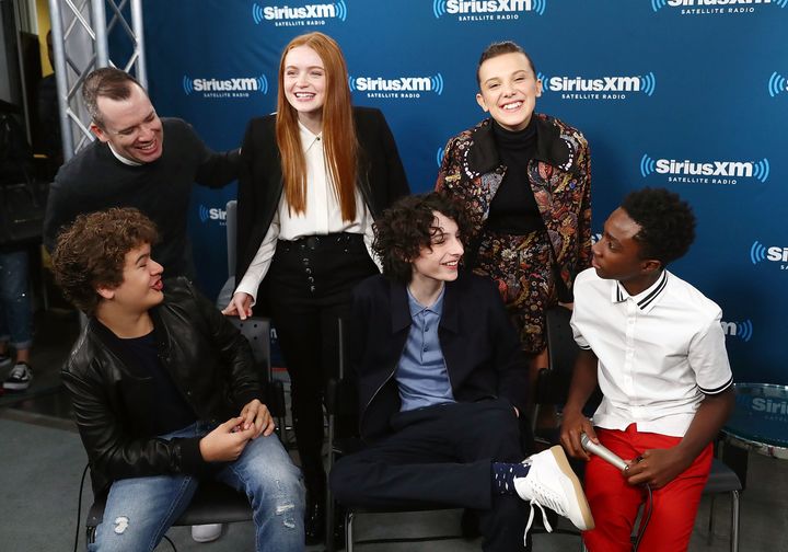 Some of the young cast members of "Stranger Things," pictured in November with host Sirius XM host Tim Stack, are getting rich.