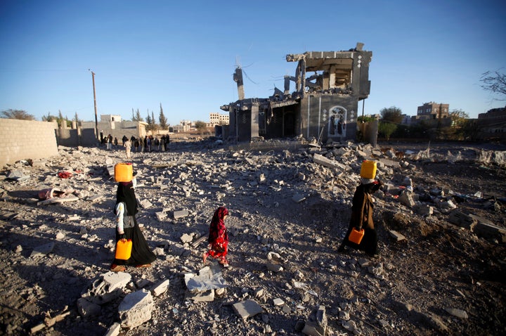 People carry water across a field of rubble north of Sanaa, Yemen, after a Saudi-led air strike on March 8, 2018.