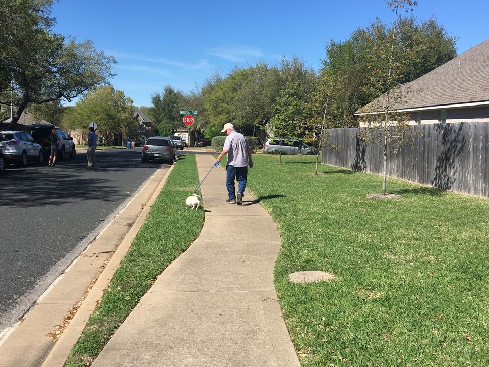 James Barnes walks his dog toward the spot where, days earlier, a tripwire bomb detonated in his sleepy neighborhood in Austin.
