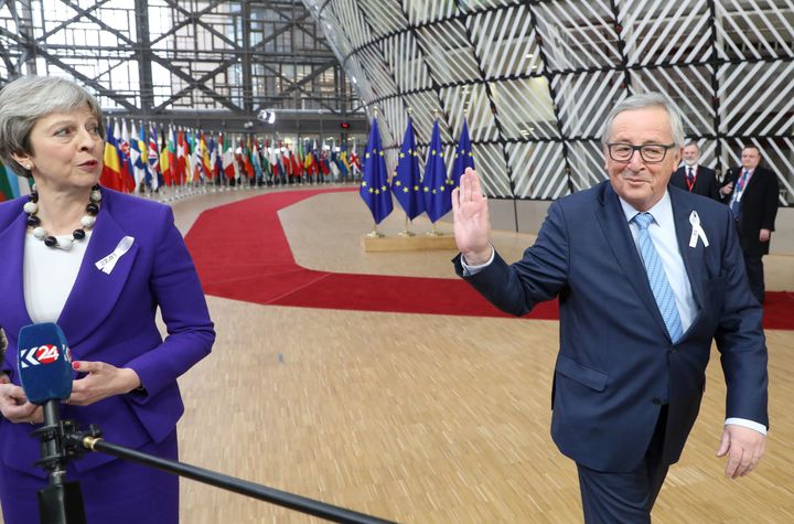 Theresa May speaks to the press as European Commission president Jean-Claude Juncker greets her as they arrive on the first day of a summit of European Union.