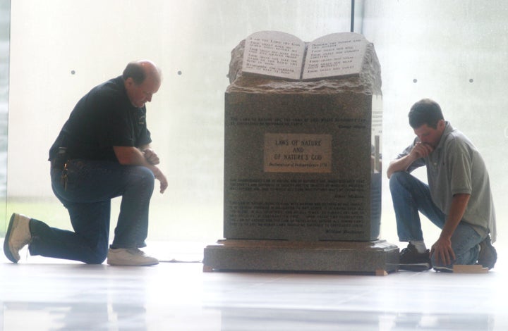 Workers pause before removing a Ten Commandments monument from the rotunda of the state judicial building in Montgomery on Aug. 27, 2003. Federal courts ordered the monument removed.