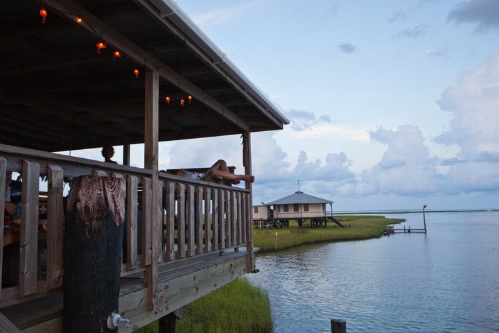 A man with his legs streched out at a fishing camp in the marsh off Isle de Jean Charles.