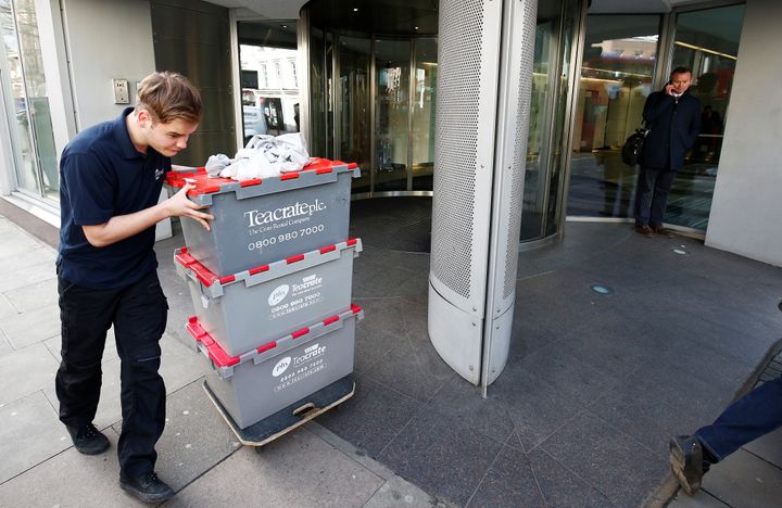 A man wheels storage crates from the building that houses the offices of Cambridge Analytica in central London on Tuesday
