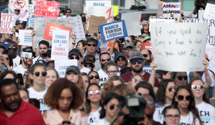 People and students hold signs while rallying in the street during the "March for Our Lives" demanding stricter gun control laws at the Miami Beach Senior High School, in Miami, Florida, U.S., March 24, 2018. REUTERS/Javier Galeano