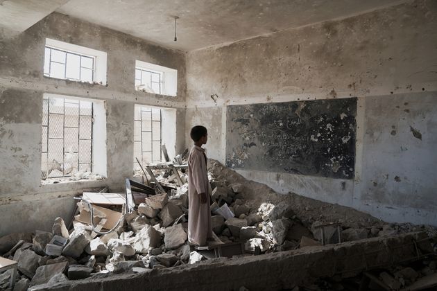 A boy stands in  the ruins of his old classroom in Saada, Yemen.