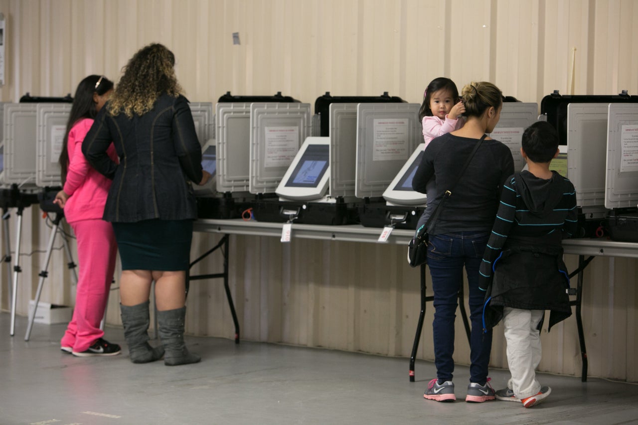 Phonexay Do, right, casts her vote with her children at the Gwinnett County Fairgrounds on Nov. 8, 2016, in Lawrenceville, Georgia.