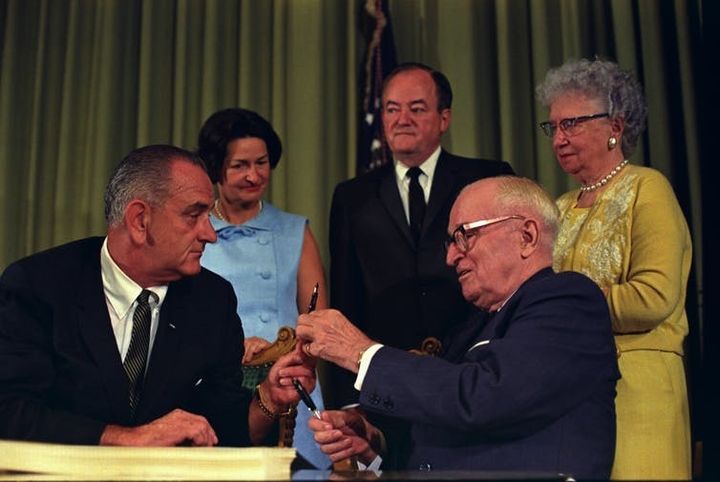 In another era, a sitting president and a former president celebrate the signing of the bill that created Medicaid. LBJ Photo Library