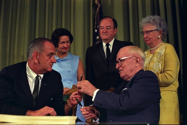 In another era, a sitting president and a former president celebrate the signing of the bill that created Medicaid. <a rel="n