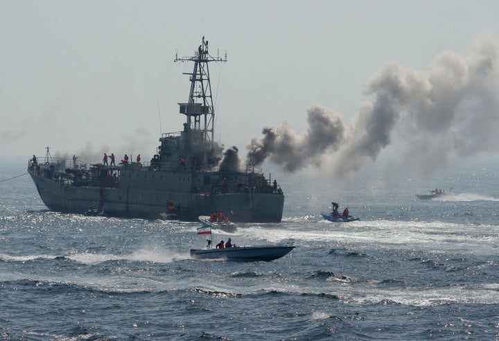 Members of Iran's Revolutionary Guard swarm around a larger naval vessel during military exercises in the Persian Gulf on April 22, 2010.