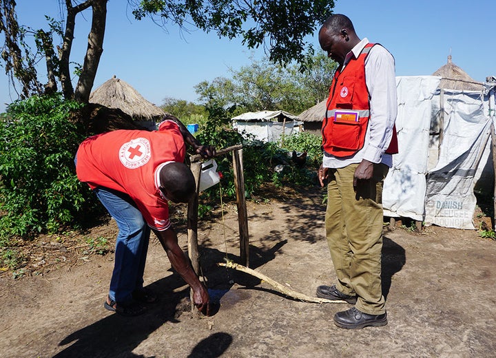 Uganda Red Cross volunteers fix a pedal-operated soap dispenser for hand washing in an effort to reduce infections