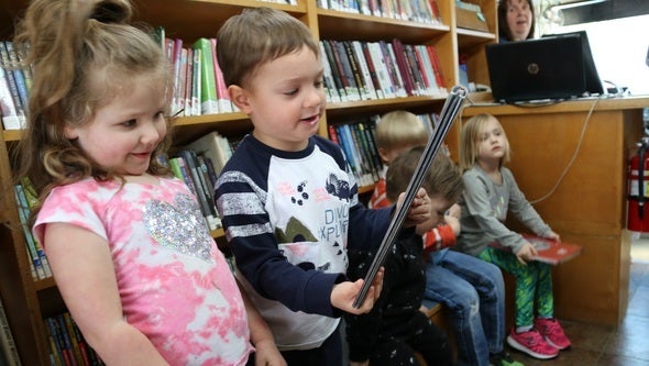 Children pick out books on the Graves County bookmobile as the librarian, Sandra Hennessee, looks on. Bookmobiles are dwindli