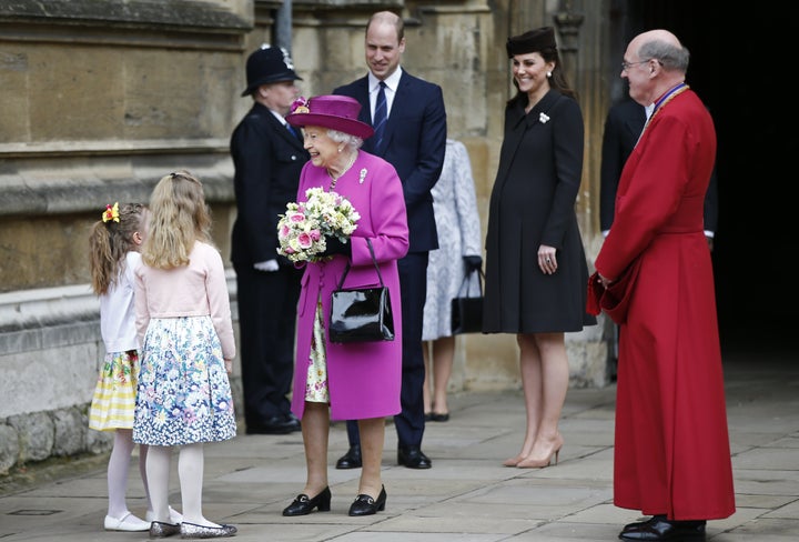 The queen wore a magenta hat and coat over a floral dress.