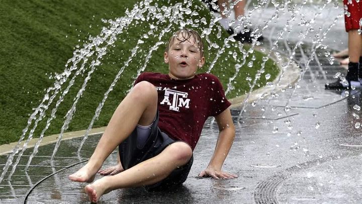 A boy plays in a water fountain in 2013 at Klyde Warren Park in Dallas, which is among the cities building “highway cap parks” to create downtown green space.