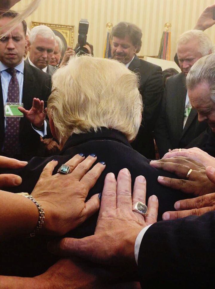 Evangelical Christians lay hands on President Donald Trump as they pray in the Oval Office on July 10, 2017.