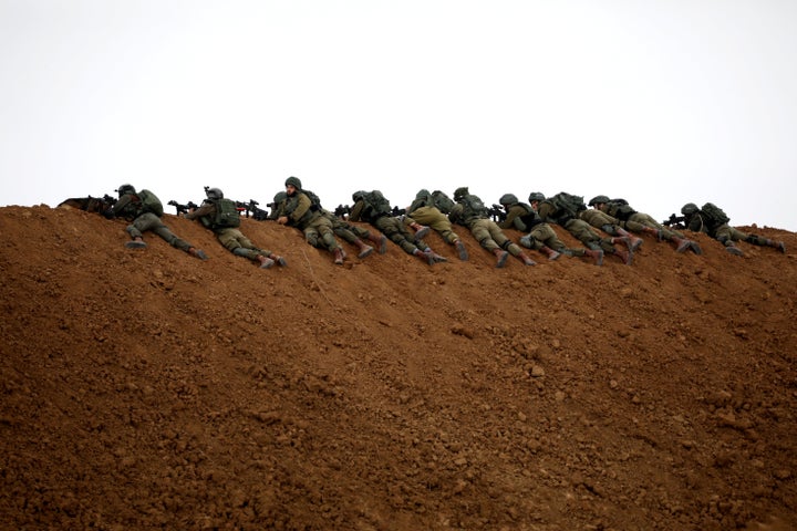 Israeli soldiers are perched atop a dune on the Israeli side of the border with the northern Gaza Strip on Friday.