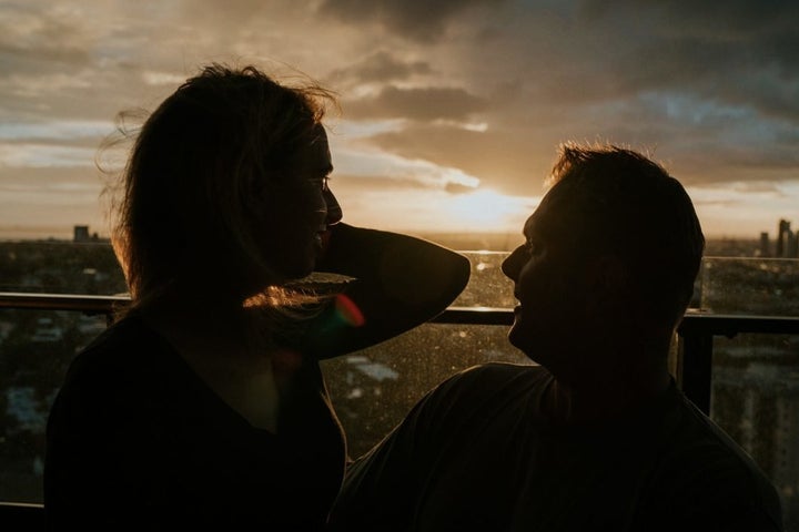 Agnew and her fiancé, Rob Campbell, are on the balcony of their apartment with the sun setting behind them. She sits on his lap as he holds her hair back from her face with one hand.