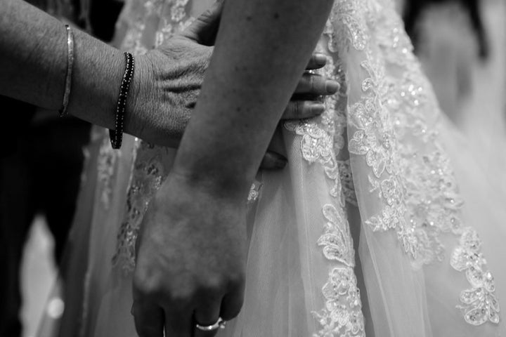 In this close-up image, Agnew's mother runs her hands along her daughter's hip as she gets a feel for how the beaded and embroidered wedding dress fits Steph.