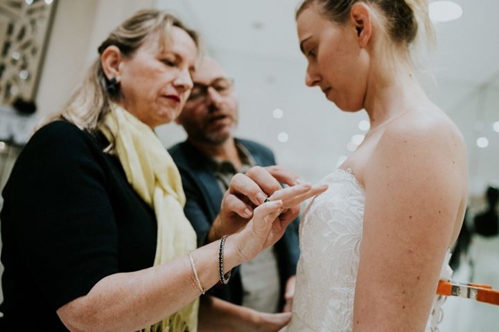 Agnew's father guides his wife's hand to the detailing on the embroidered bodice of a gown their daughter is trying on.