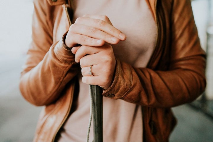 Agnew is shown in a close-up with her right hand atop her cane with her left hand, adorned with her engagement ring, below it.