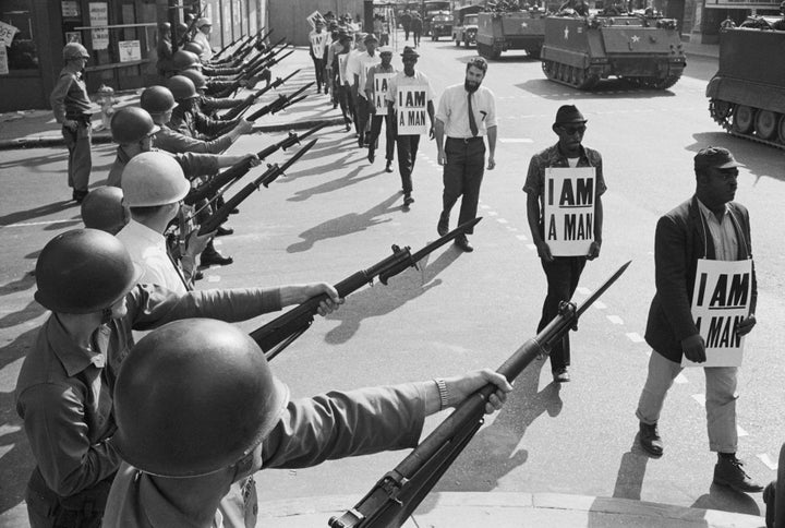 U.S. National Guard troops block off Beale Street in Memphis as civil rights marchers wearing placards reading "I AM A MAN" pass by on March 29, 1968.