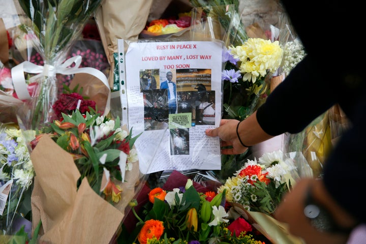 A family friend looks at a message left at a temporary memorial, set up at a spot near to where 18 year old Israel Ogunsola was stabbed to death on Wednesday