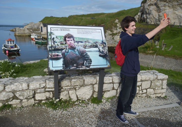 A Game of Thrones fan takes a 'selfie' beside a plaque at Ballintoy Harbour on August 13, 2015 in Belfast, Northern Ireland.&