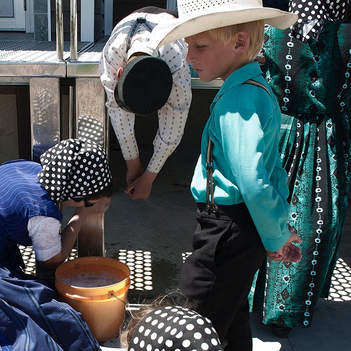 Hutterite children help clean farming equipment.