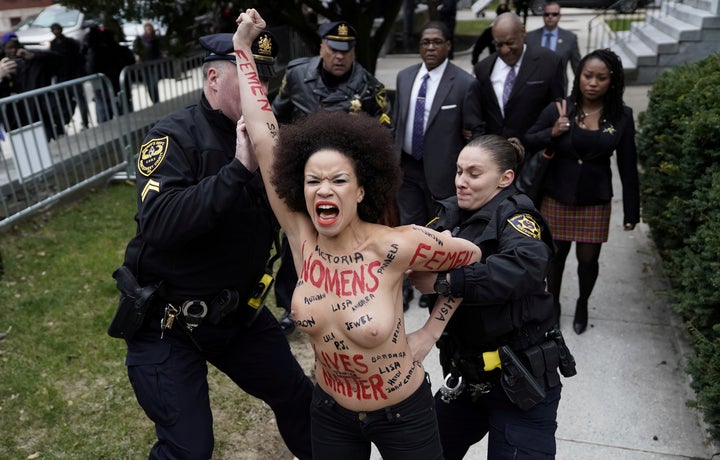 Protester Nicolle Rochelle is subdued by police after breaking through the barriers as Cosby arrived on his first day of his